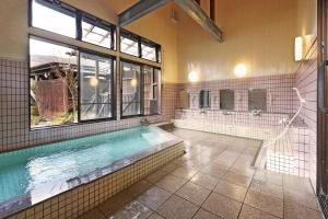 een grote badkamer met een zwembad en een raam bij 旅館 家族湯 いまむら in Yamaga