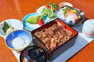 een tafel met een dienblad met eten en kommen met eten bij 旅館 家族湯 いまむら in Yamaga