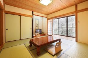 een eetkamer met een tafel, stoelen en ramen bij 旅館 家族湯 いまむら in Yamaga