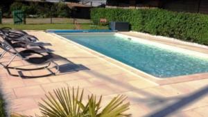 a large swimming pool with lounge chairs next to it at Gîte soline avec piscine chauffée in Saint-Riquier