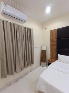 ハーイルにあるروعة أجا للشقق المخدومة غرفة وصالةのベッドとカーテンのついた窓のある寝室