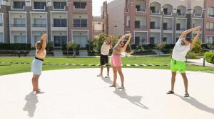 Marsa AlamOyster Bay Beach Suites的一群人在建筑物前摆出瑜伽姿势。