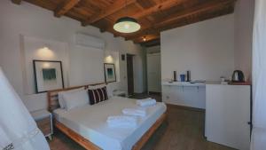 a bedroom with a white bed and a kitchen at Gulhiz in Datca