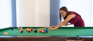 a woman standing over a pool table with a cue at Oyster Bay Beach Suites in Marsa Alam