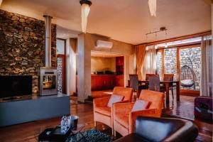 a living room with orange chairs and a stone wall at Forum Homini Boutique Hotel in Krugersdorp