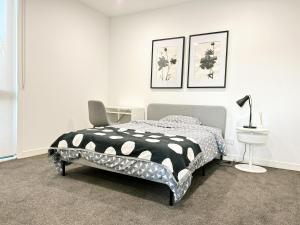 库克角Skyline Loft I HERstay in Point Cook的一间卧室，配有一张床、一张桌子和一把椅子