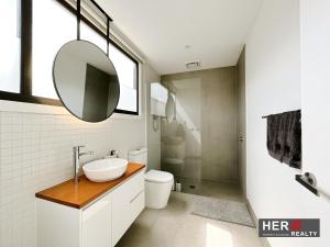 库克角Skyline Loft I HERstay in Point Cook的浴室里有洗手池、马桶和镜子。