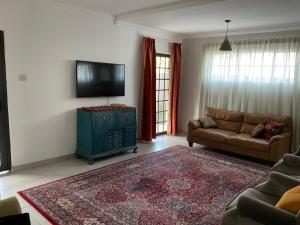 a living room with a couch and a flat screen tv at Ginnys Place in Gaborone