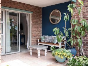a porch with a bench and plants and a mirror at Bluewater Guesthouse in Port Elizabeth
