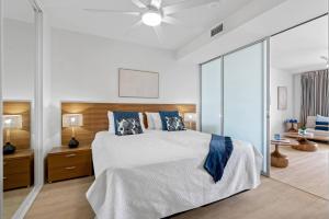 una camera da letto con un grande letto bianco con cuscini blu di Marina Vista - Waterfront Stay near Dining and Markets a Cairns Altre 18 foto