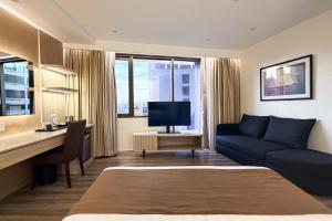 um quarto de hotel com uma cama, uma escrivaninha e um sofá em City Garden Hotel Makati em Manilla