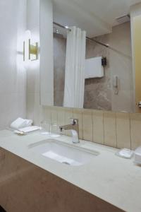 um banheiro com uma pia e um espelho em City Garden Hotel Makati em Manilla