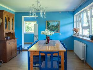 a blue dining room with a wooden table and blue chairs at Viesu māja Vanaturs in Roja