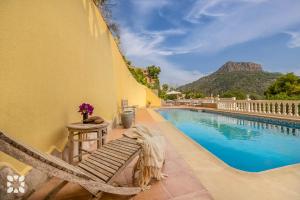 a pool with a hammock next to a building at Villa Cala Encantada Sea View Apartments with Pool in Calpe