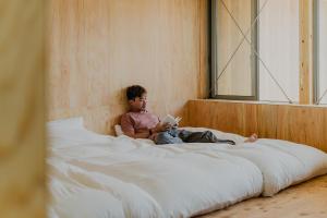 a child sitting on a bed reading a book at SANU 2nd Home Ichinomiya 2nd in Ichinomiya