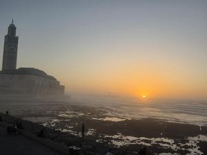 a sunset with a clock tower and the ocean at Luxury 1 bedroom at La marina in Casablanca