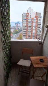 a balcony with a table and chair and a large window at Apartman 43 in Kraljevo
