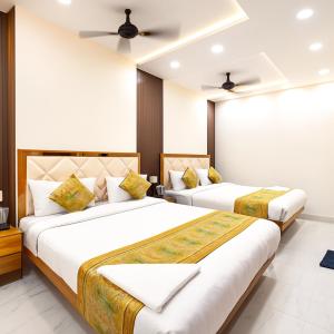 due letti in una stanza con pareti bianche di HOTEL BNK GRAND Near Goḏawalia Chauraha - 100 Meter From Baba Vishwanath Temple & Ganga Arti Ghat ! Wi-Fi #Lift #Hygiene & Spacious Room - BEST HOTEL IN VARANASI a Varanasi Altre 24 foto