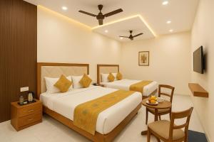 una camera d'albergo con due letti e un tavolo di HOTEL BNK GRAND Near Goḏawalia Chauraha - 100 Meter From Baba Vishwanath Temple & Ganga Arti Ghat ! Wi-Fi #Lift #Hygiene & Spacious Room - BEST HOTEL IN VARANASI a Varanasi