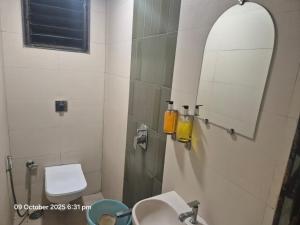 a bathroom with a sink and a mirror and a toilet at Hotel Sai Pratham in Shirdi