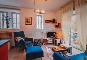 a living room with blue chairs and a television at Location Appartement Les Ondes in Albertville