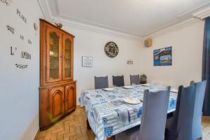 a dining room with a table and chairs and a clock at Maison pour 6 avec grand jardin - proche centre in Plouguerneau +11 photos