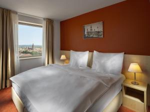 Un dormitorio con una gran cama blanca con ventana. en Clarion Congress Hotel České Budějovice, en České Budějovice