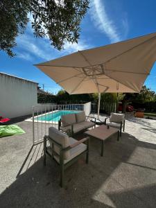 Una sombrilla grande, sillas, una mesa y una piscina. en Chambre individuelle avec coin repas et entrée privative dans Villa avec Piscine WC & SDB communs, en Vitrolles
