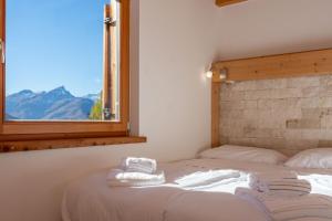 a bed with towels on it in a room with a window at Wonderful appartment Monte Civetta in Dolomites in Alleghe