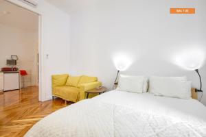 a bedroom with a white bed and a yellow chair at MEZZANINE ORANGE in Madrid