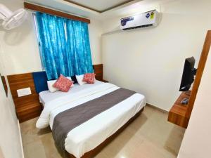 a bedroom with a large bed with a blue curtain at Hotel Shree Maya Inn in Vadodara +6 photos