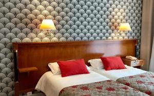 zwei Betten mit roten Kissen in einem Hotelzimmer in der Unterkunft Logis Hotel Diana in Vence