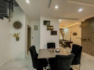a dining room with a table and chairs and a piano at Blooms Manor Apartments in Lagos
