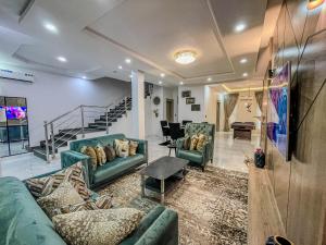 a living room with green couches and a staircase at Blooms Manor Apartments in Lagos