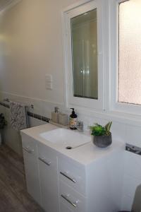 een witte badkamer met een wastafel en een spiegel bij Nonna's Cottage 