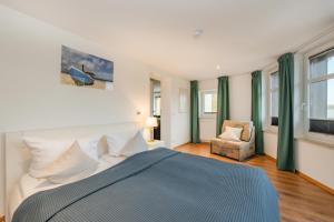 a bedroom with a bed and a chair and windows at Ferienhaus Ingrid in Heringsdorf