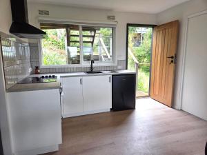 a kitchen with white cabinets and a sink and a window at Jalpari in McCrae