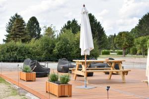 Campingfass im Naturresort Weserinsel في Langwedel: مظلة على سطح خشبي مع طاولة ومقاعد