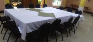 una gran mesa blanca con sillas negras en una habitación en Snow Peak Hotel in Chogoria, en Mwangarimwe