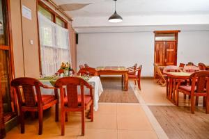 Un comedor con mesas y sillas de madera. en Snow Peak Hotel in Chogoria, en Mwangarimwe