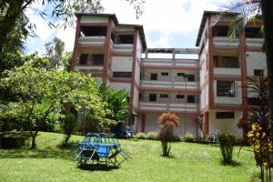 Un edificio rosa con una mesa azul delante. en Snow Peak Hotel in Chogoria, en Mwangarimwe