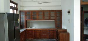 a kitchen with wooden cabinets and a black refrigerator at Villa Coconut Tree in Angulugaha