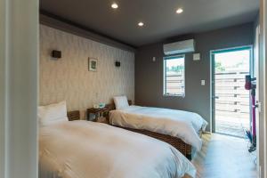 Un dormitorio con dos camas y una ventana. en Alezed Villa Shiraho, en Ishigaki Island