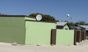 a green wall with a clock on top of it at Namasiku 's Self Catering in Khomas Region