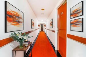 Un pasillo con alfombra naranja y cuadros en las paredes. en FabHotel F9 NFC, en Nueva Delhi