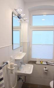 Kapitaenshaus-Lassen-Zimmer-Amistad في فيسترلاند: حمام مع حوض ومرآة ونافذة