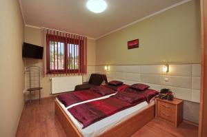 um quarto com uma cama grande com travesseiros vermelhos em Babilon Gyula Szállás De Luxe em Gyula