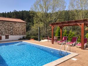 a pool with chairs and a pavilion next to a house at Casa Lerryn in Sertã