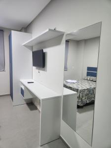 a white room with a bed and a desk and a mirror at West Fit Padrão 06 in Mossoró