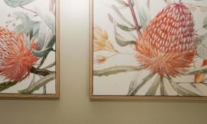 two paintings of flowers are hanging on a wall at Beacon Point House in Port Campbell